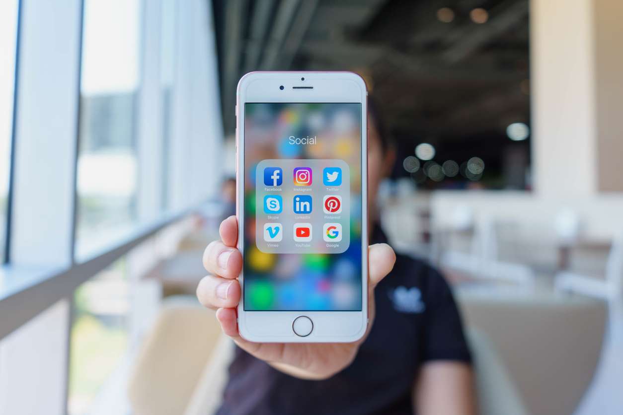 Woman holding Apple iPhone 6S Rose Gold with icons of social media on screen. Social media are most popular tool. Smartphone life style. Starting social media app.