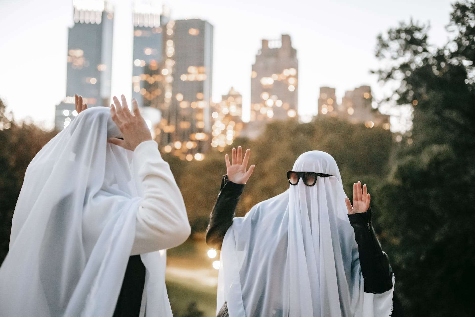 cheerful anonymous couple in ghost costumes having fun on street